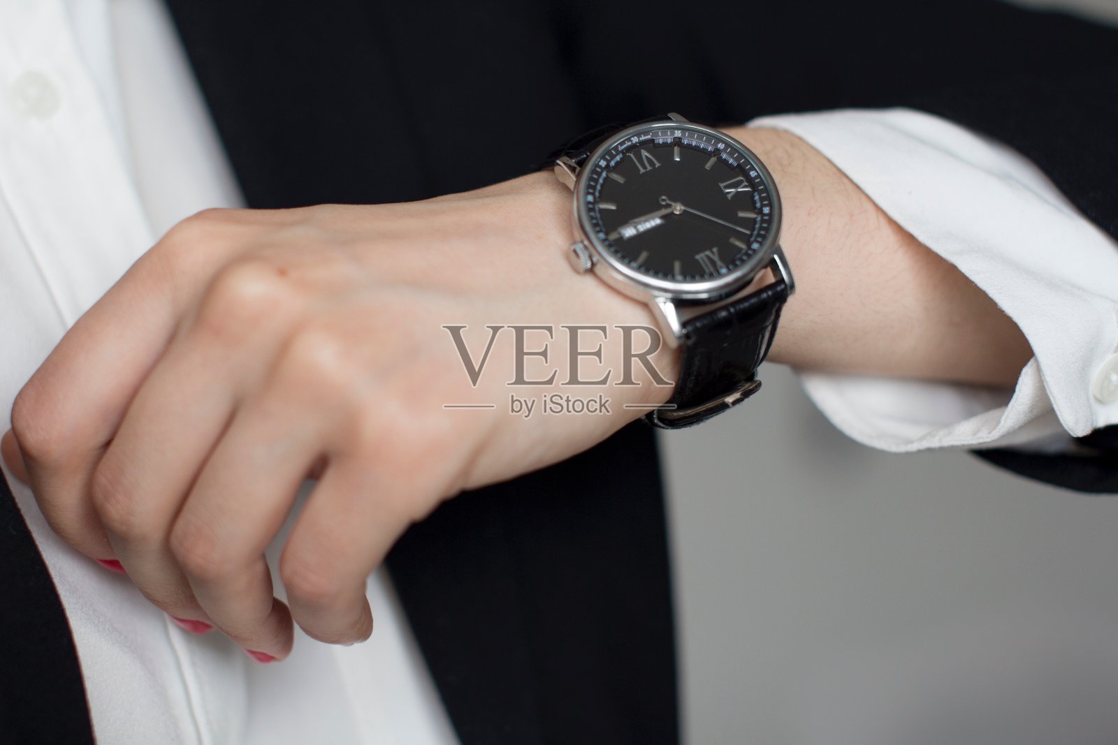 穿黑西装的年轻女子检查时间到了照片摄影图片