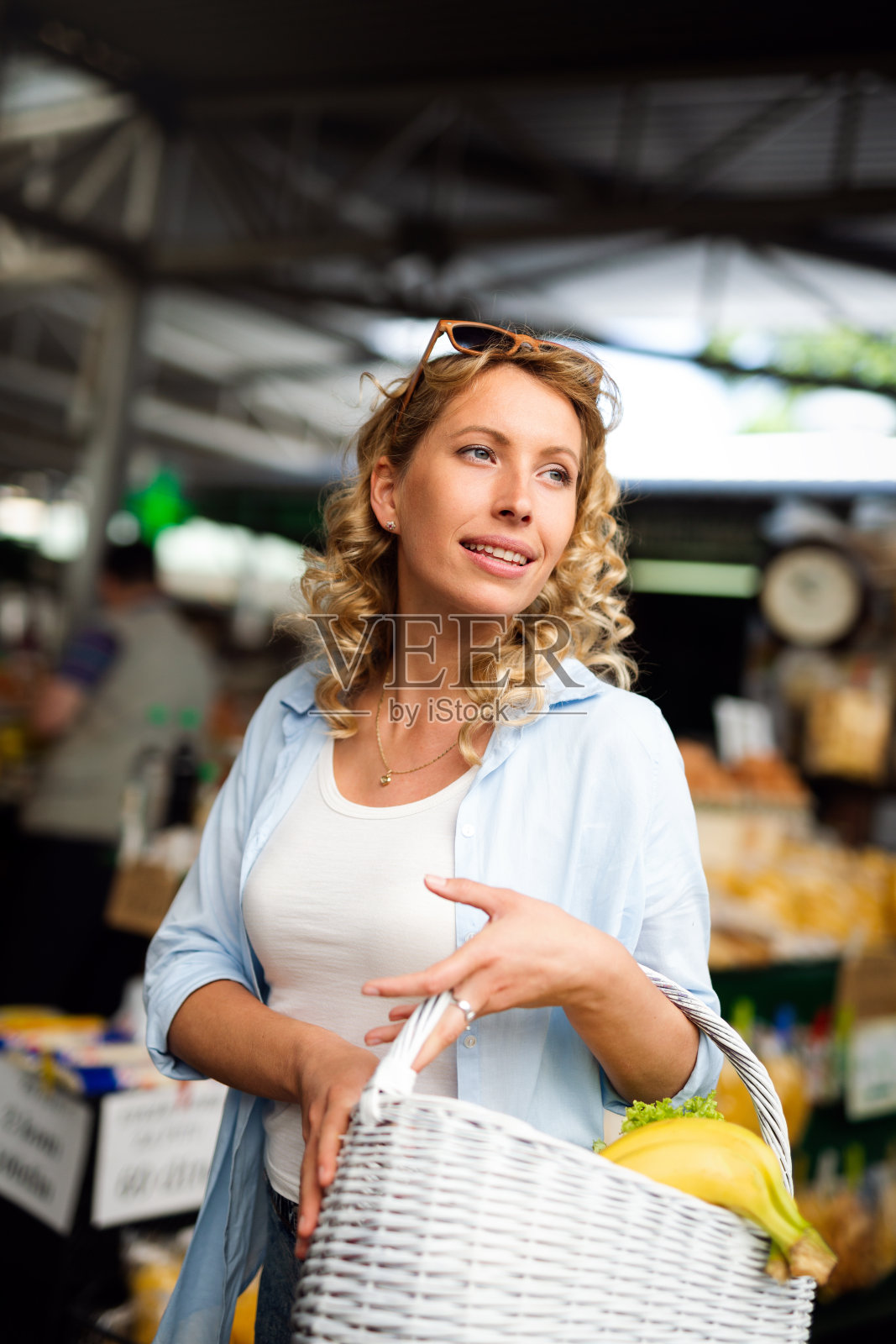 年轻女子在市场的摊位上买菜照片摄影图片