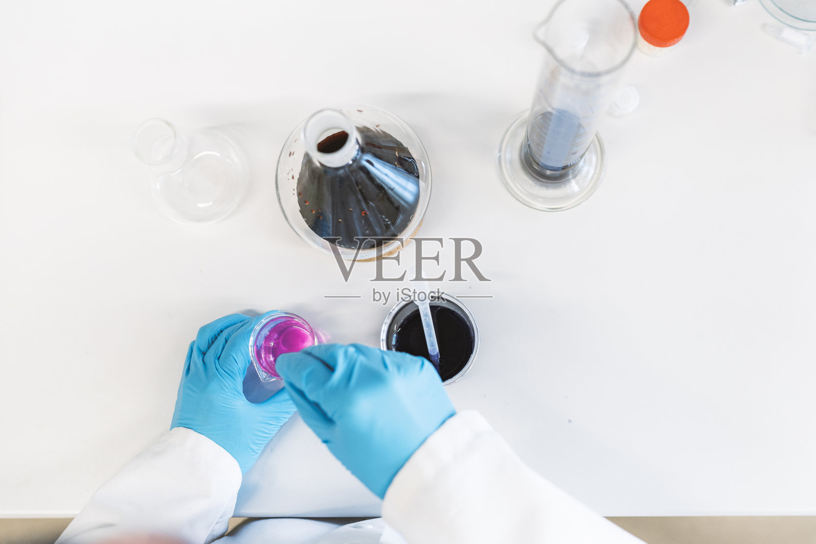 戴着手套研究液体化学品的科学家的手照片摄影图片