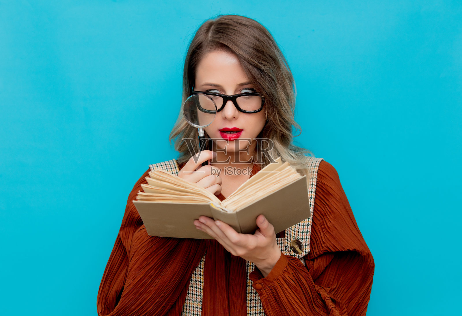 拿着放大镜和书的年轻女子照片摄影图片