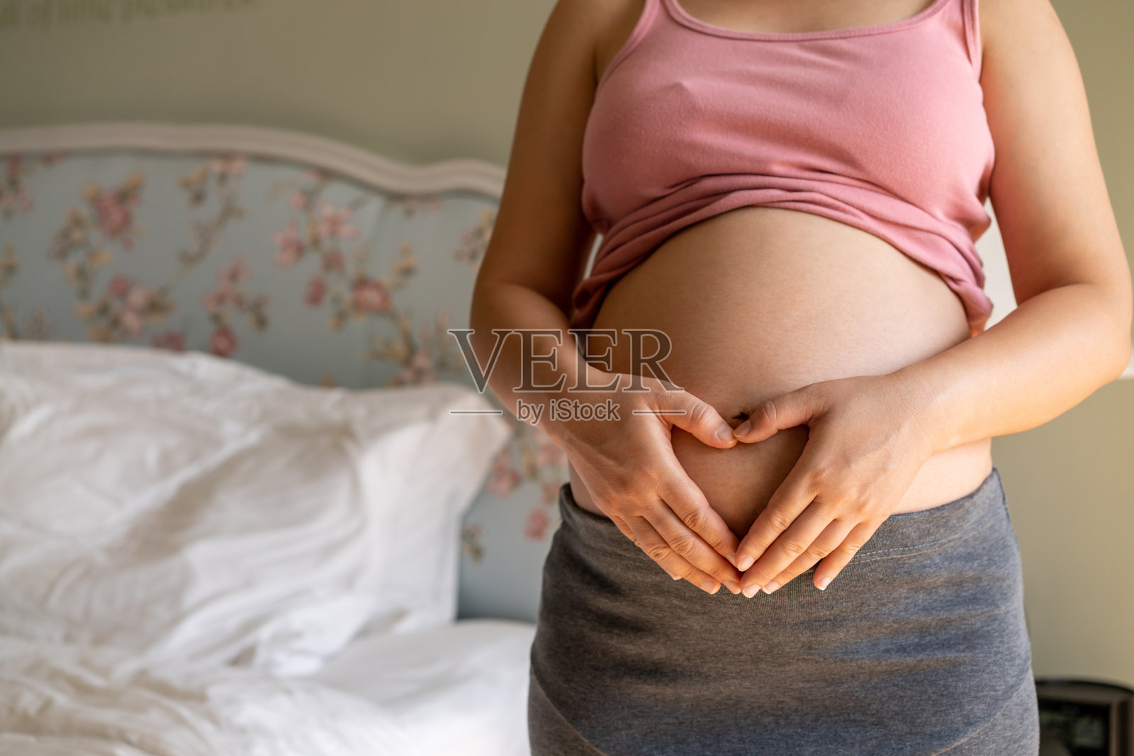 孕妇在家照顾孩子时感到快乐。年轻的孕妇抱着怀孕的肚子里的婴儿。孕产妇产前护理与妇女怀孕的概念。照片摄影图片