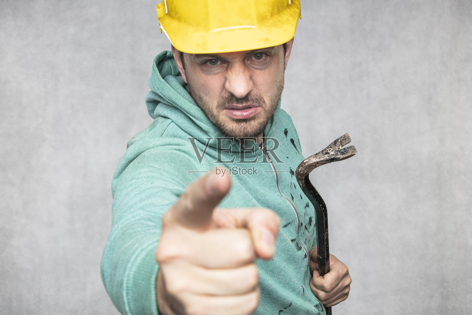 一个手里拿着撬棍的建筑工正指着你照片摄影图片