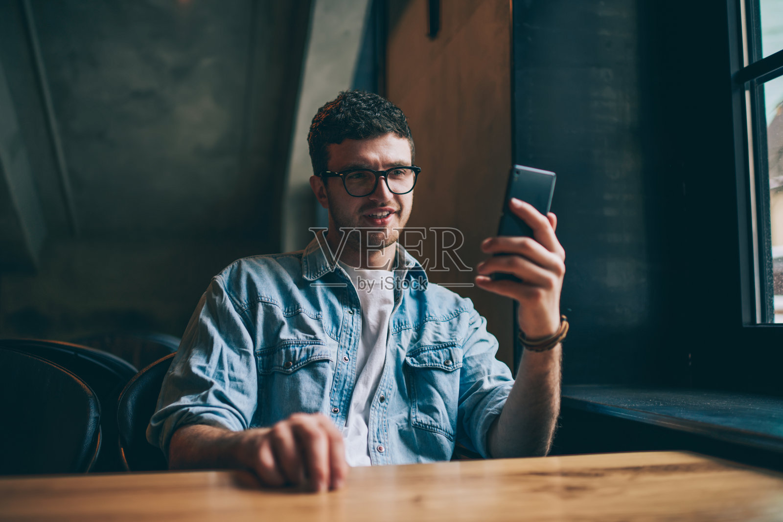 快乐开朗的潮男通过连接到无线4g网络的手机应用看搞笑喜剧,在室内用现代智能手机和最好的朋友发短信照片摄影图片