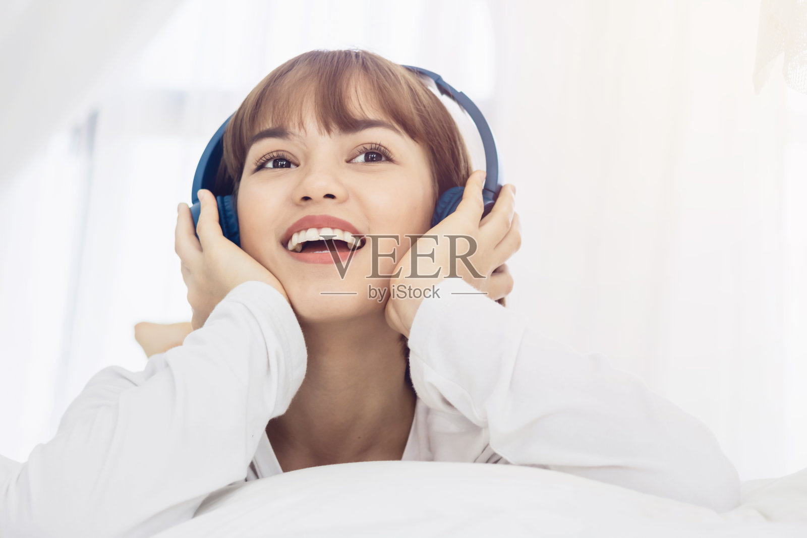 美丽的亚洲女人躺下,听音乐的sartphone与网络连接收音机。生活方式的概念。色调照片摄影图片