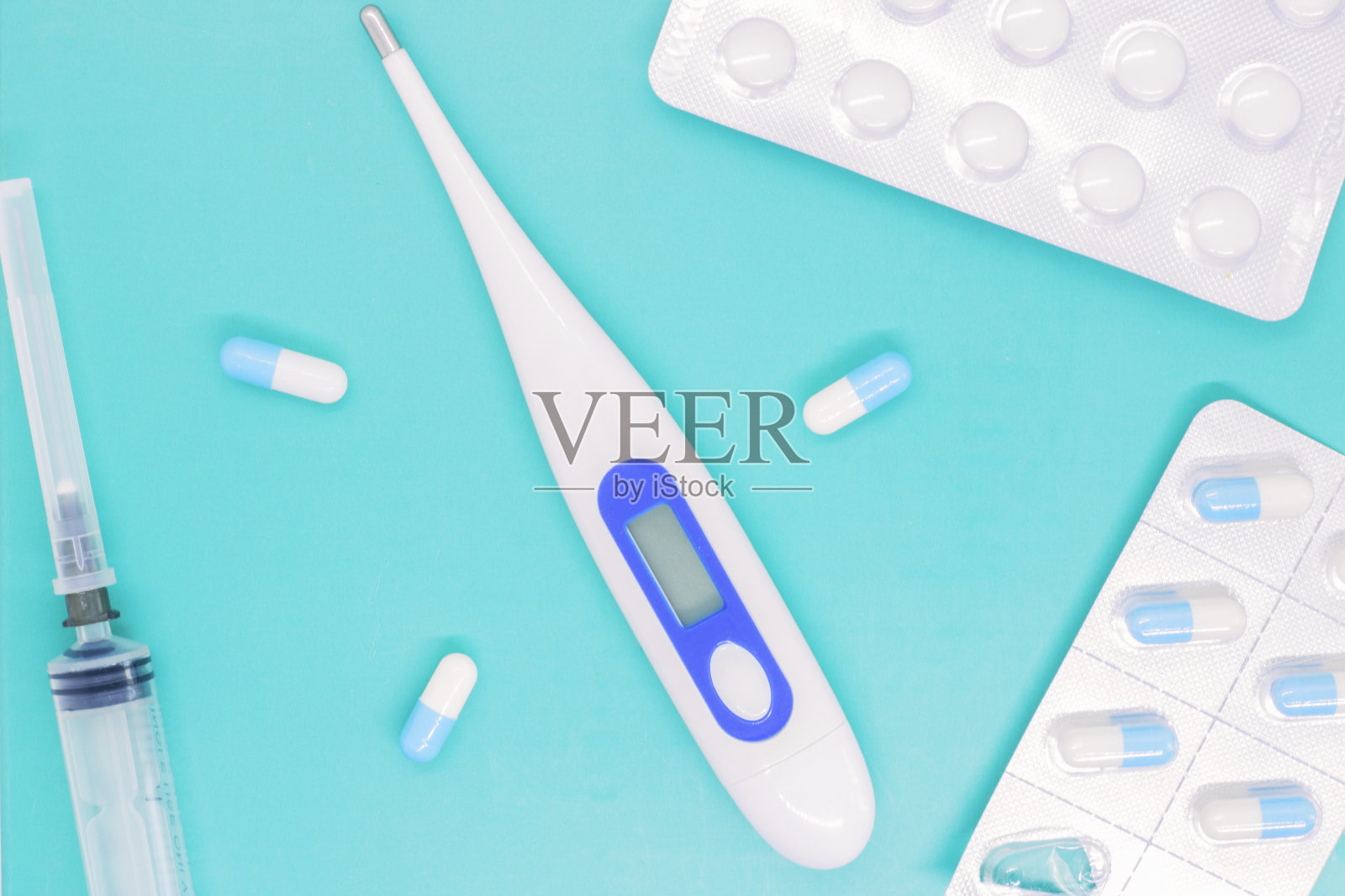 近距离的医疗设备摊开在桌子上,药品和设备放在蓝色的表面上,温度计用来测量温度,照片摄影图片