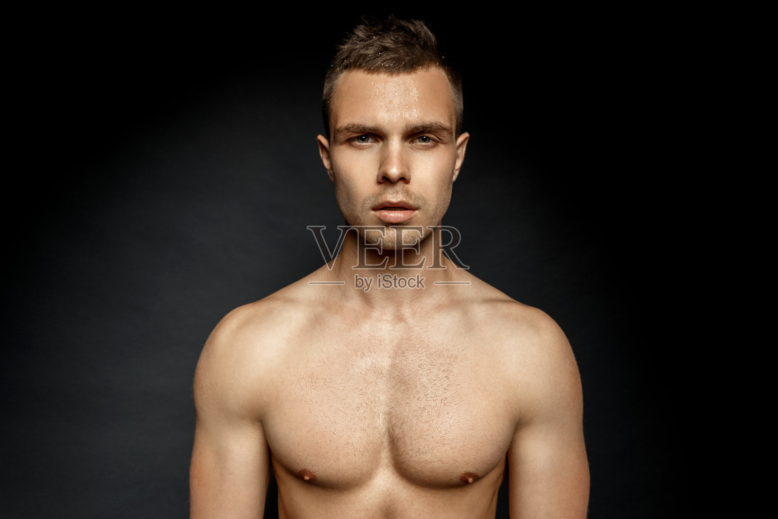 英俊的运动性感的男子肖像在水与化妆品在孤立的黑色背景照片摄影图片