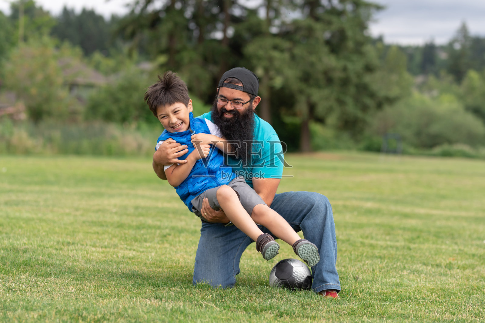 爸爸和他的儿子在公园踢足球照片摄影图片