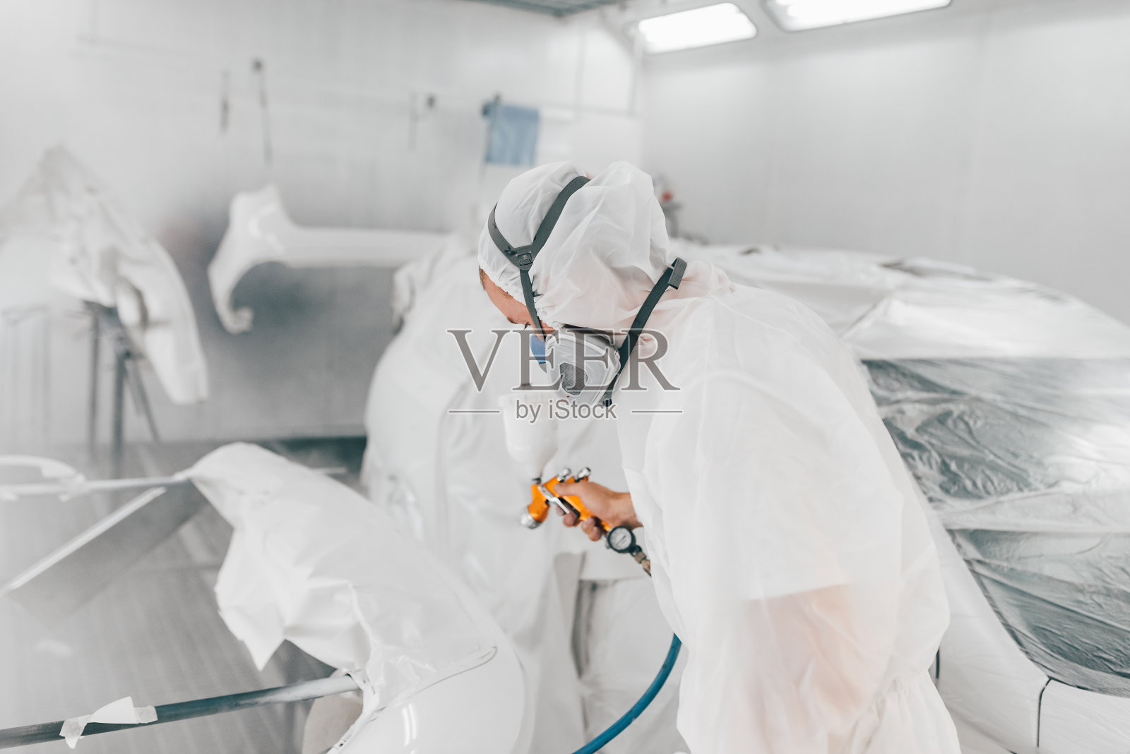 工人在汽车零件上喷漆。照片摄影图片