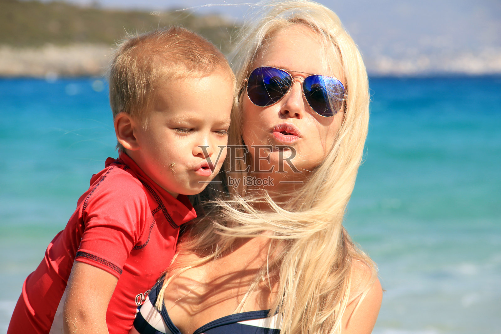 年轻的母亲和她的孩子一起玩和玩在海边在暑假时间。带着孩子过节,为人父母的观念照片摄影图片