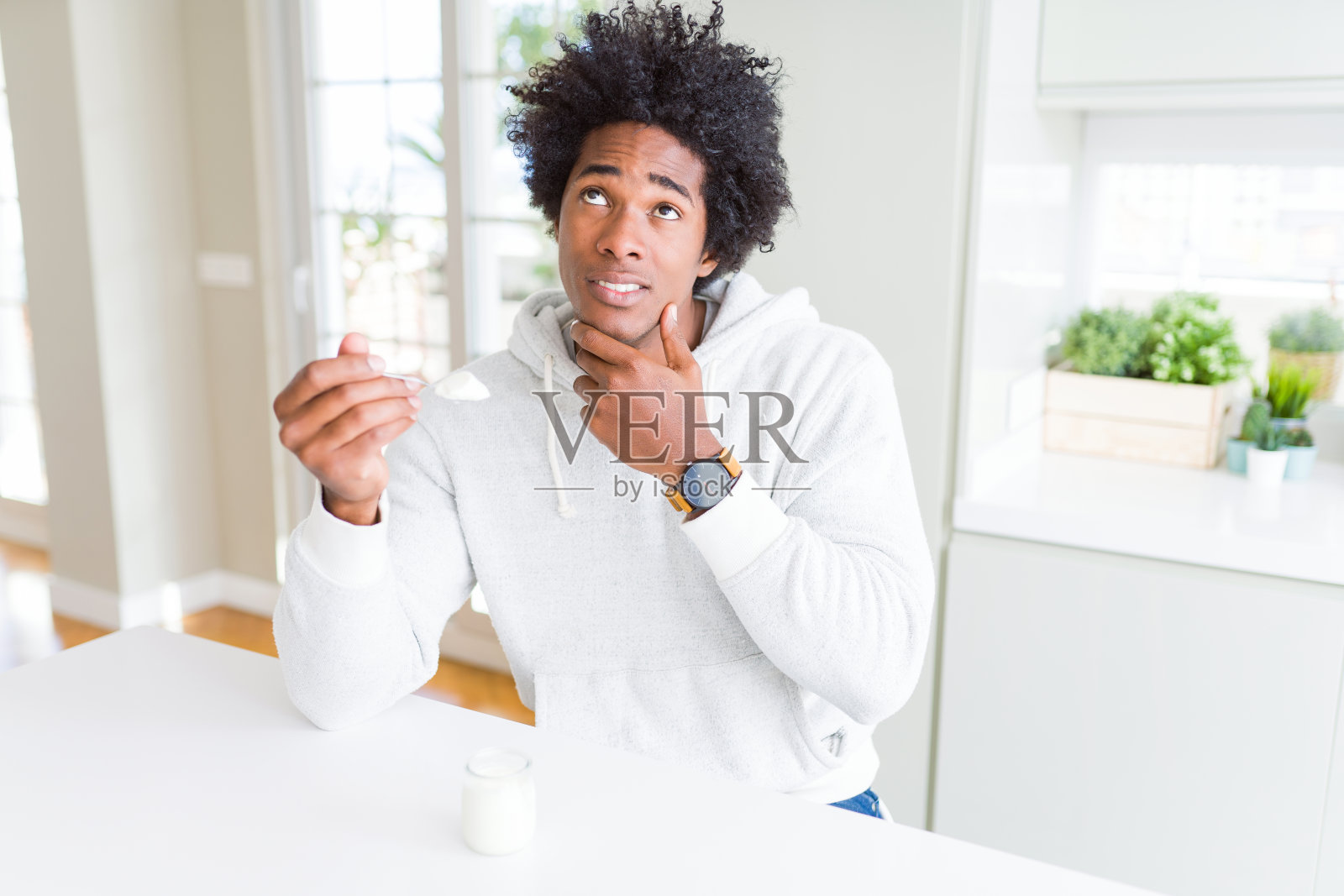 非裔美国人早餐吃健康酸奶严肃地面对思考问题,非常困惑的想法照片摄影图片