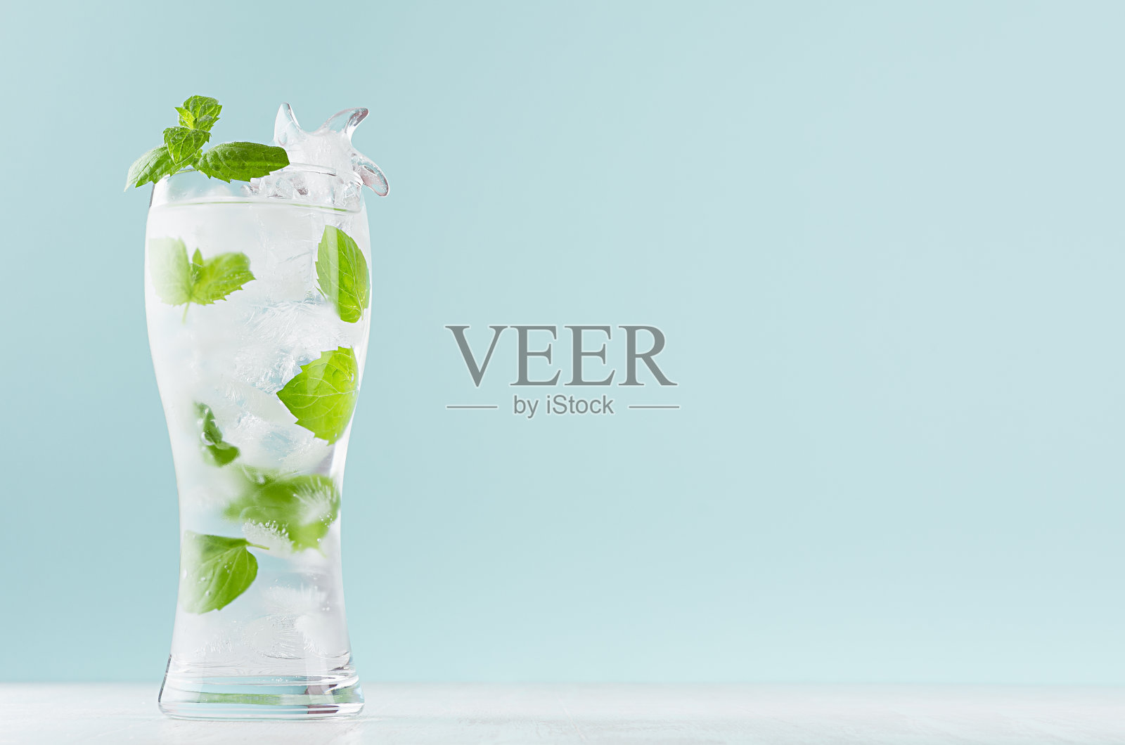 有机气泡水与薄荷绿叶,冰块,气泡水在雾蒙蒙的玻璃在现代薄荷颜色内部。照片摄影图片