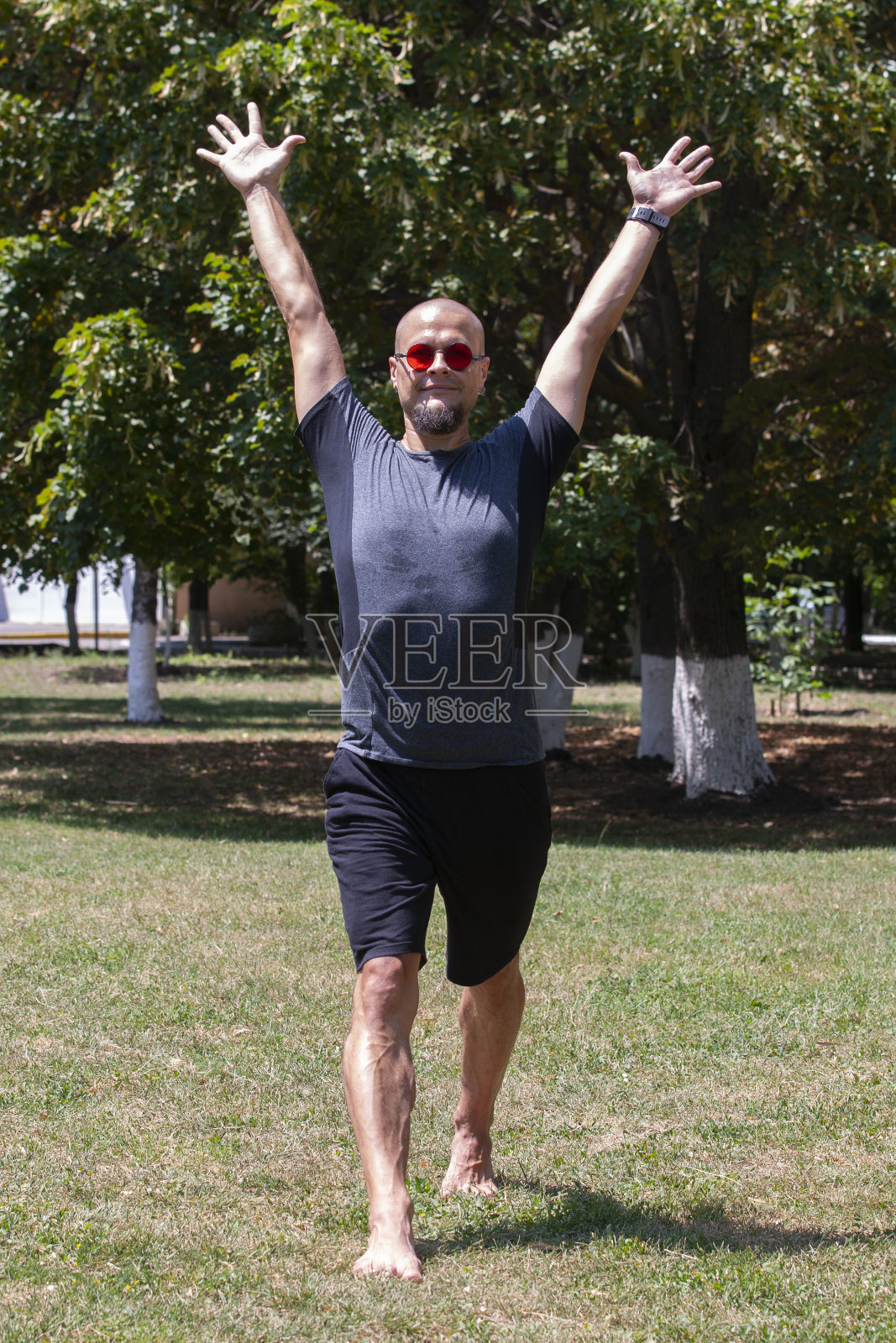 年轻人在户外练习瑜伽。运动的家伙在操场上的蓝色瑜伽垫上做伸展运动。照片摄影图片