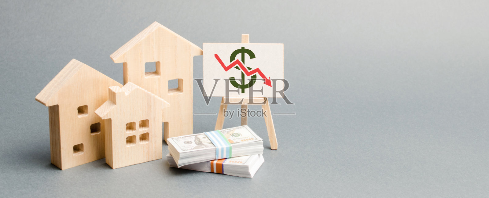 有箭头和木屋的海报。房地产市场下跌的概念。降低抵押贷款的利息。房地产价格的下跌。贷款利率低。需求减少照片摄影图片