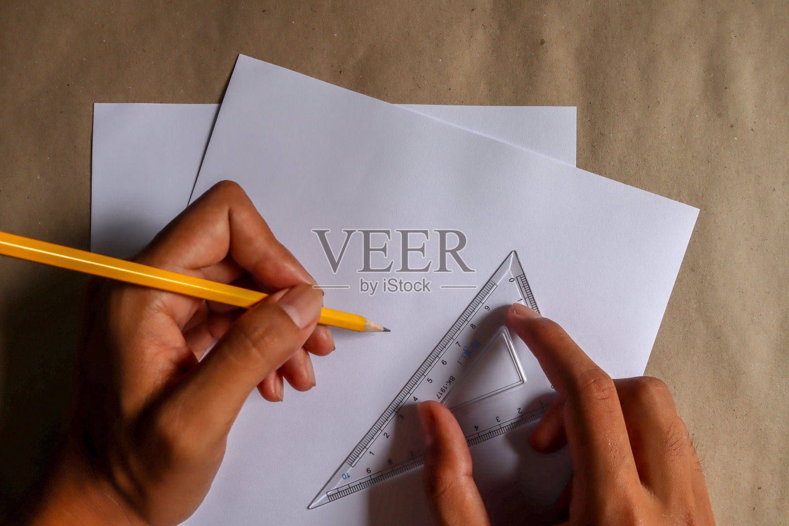 用铅笔、尺子和教育器材的人的手,写在白纸上,棕色的背景上。照片摄影图片