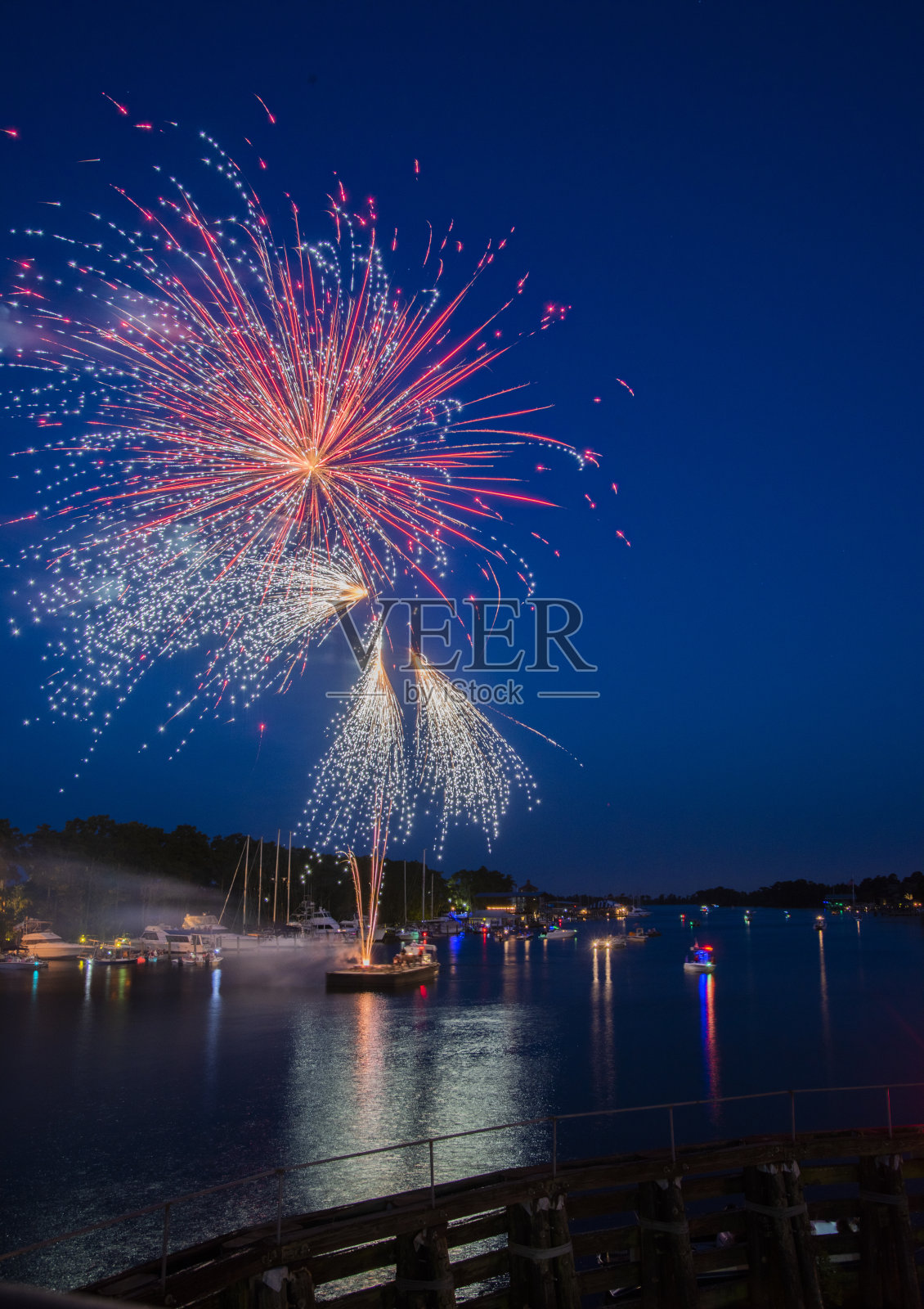 五颜六色的烟花从驳船上发射,在河水中倒映照片摄影图片