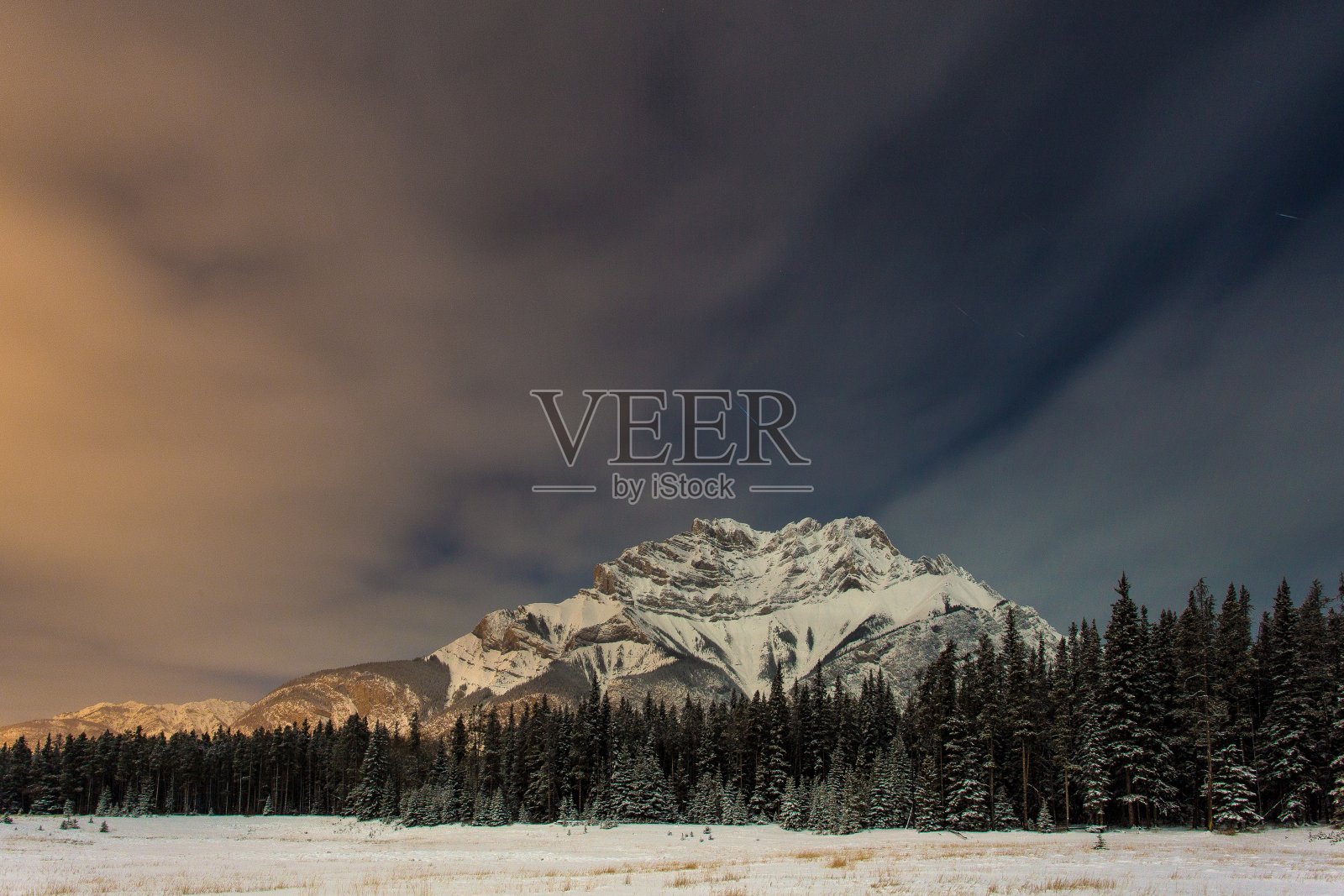 视野穿过冰冻的田野到森林和雪山照片摄影图片