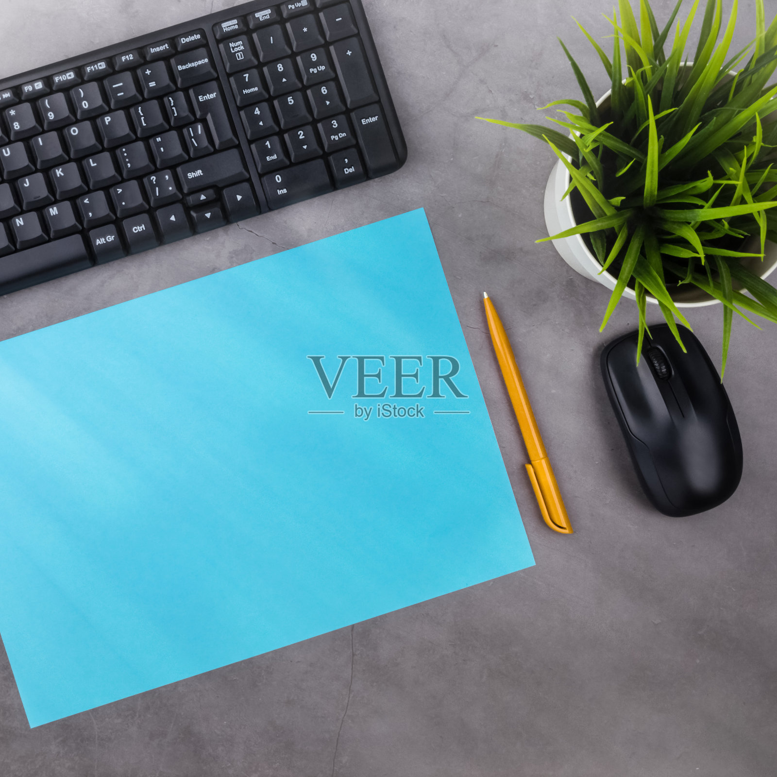 工作地点在深色的桌子上,有复印空间。键盘,鼠标,笔,纸,花盆里的花。俯视图,太阳光线从侧面。照片摄影图片