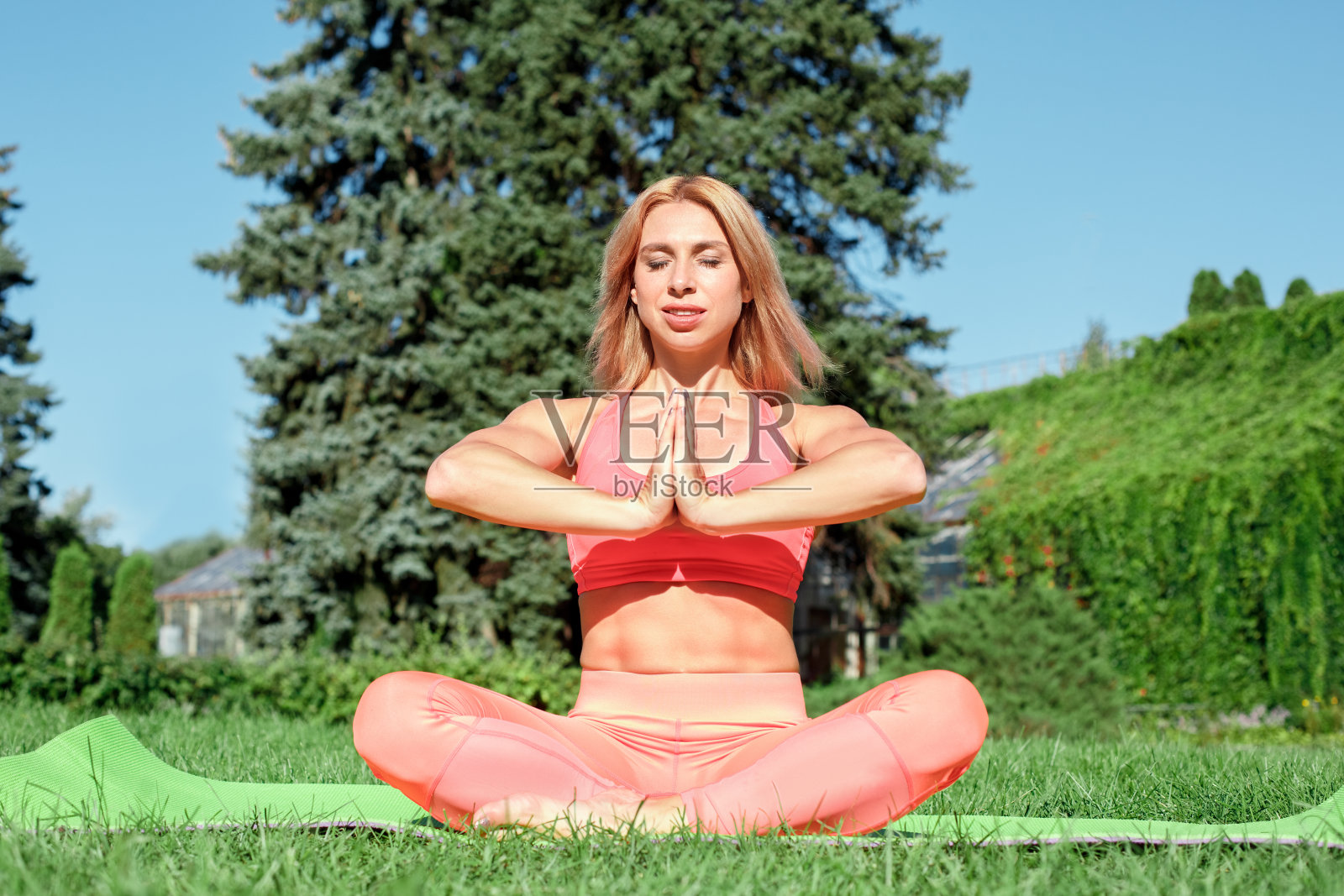 健康的生活方式。女人在户外的垫子上练习瑜伽,闭着眼睛做冥想快乐照片摄影图片