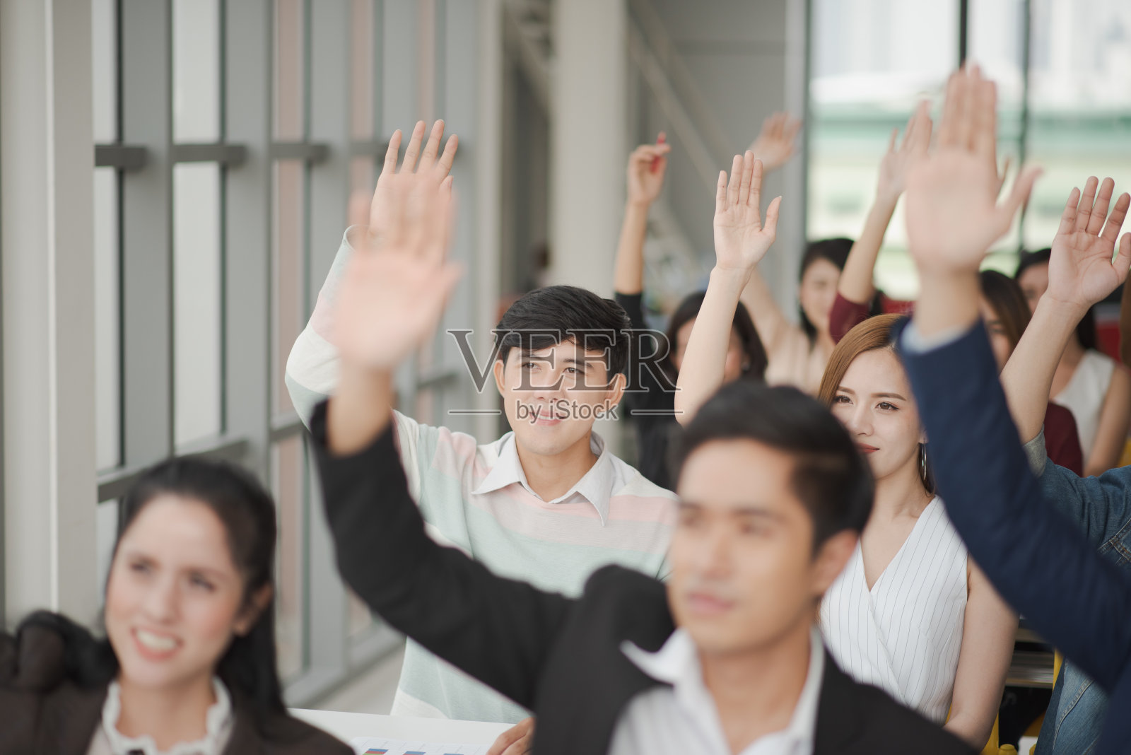 研讨组的亚洲青年举手问演讲者问题,在会议室回答时间,在培训班有问题。商务研讨会和培训理念。照片摄影图片