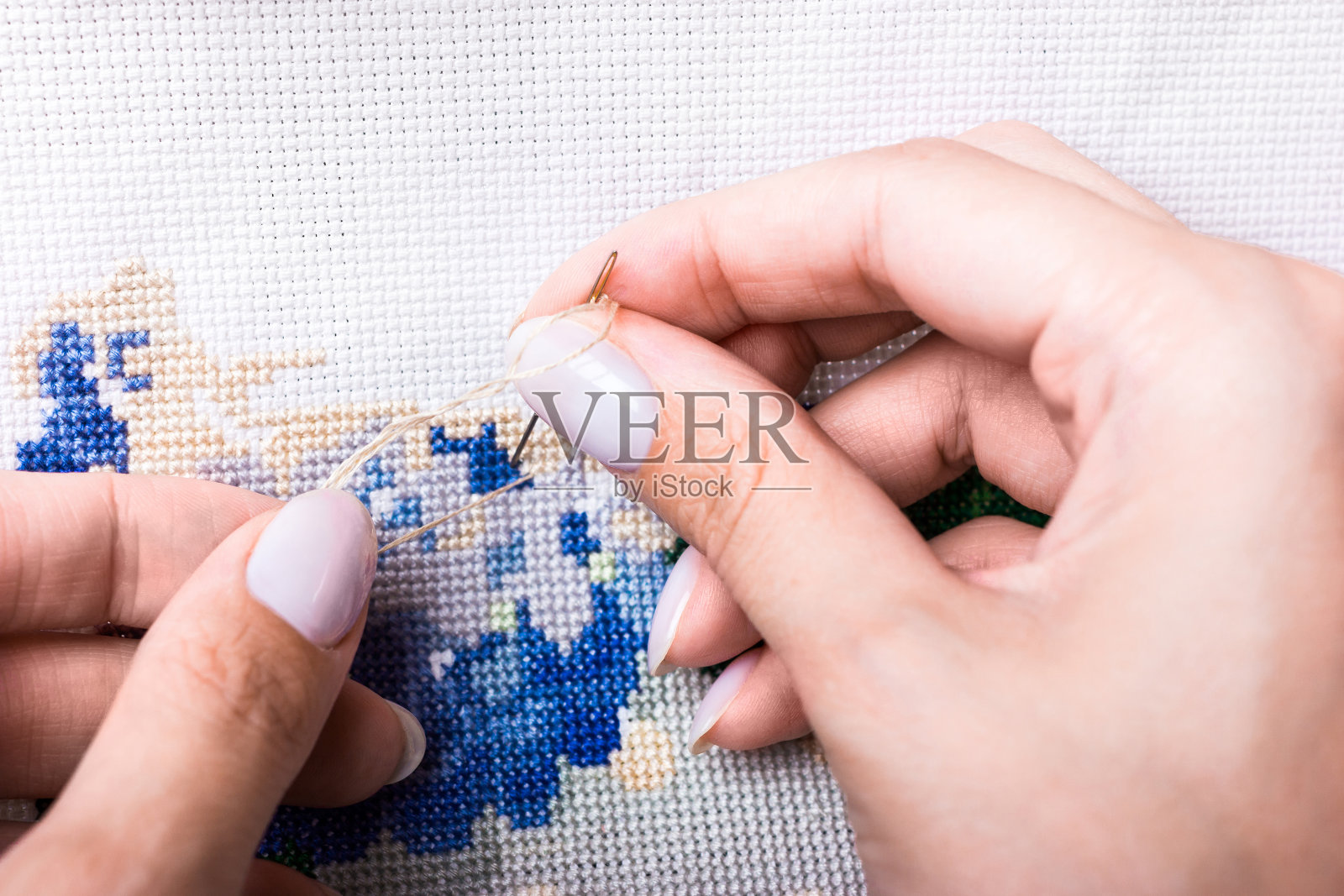 画布上的十字绣。这个女孩用线和针刺绣照片摄影图片