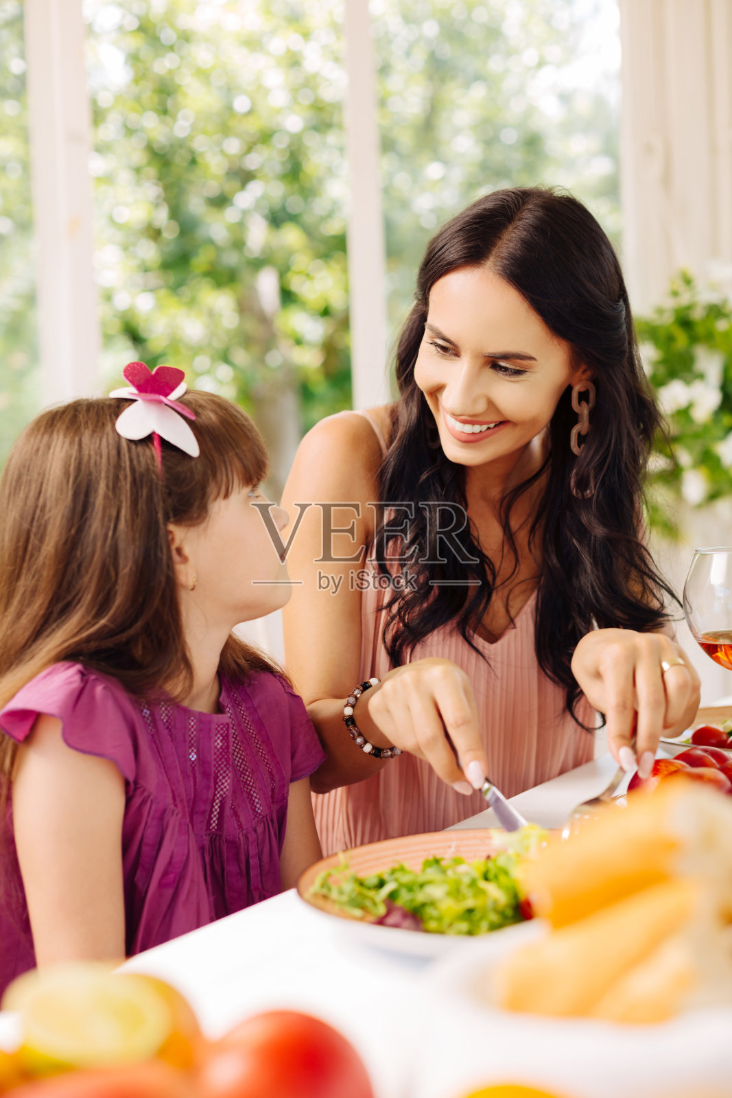 母亲微笑着给女儿做沙拉照片摄影图片