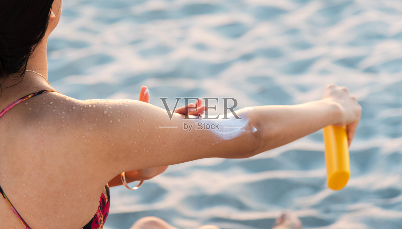 女人在海滩上使用防晒霜照片摄影图片