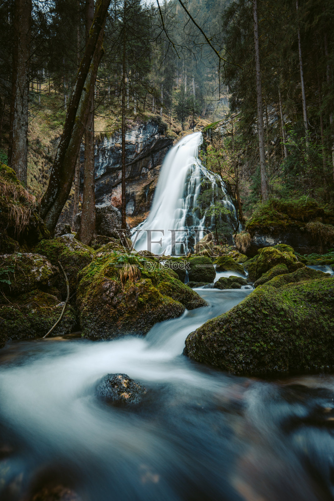 森林中长满青苔的岩石和田园诗般的瀑布景色照片摄影图片