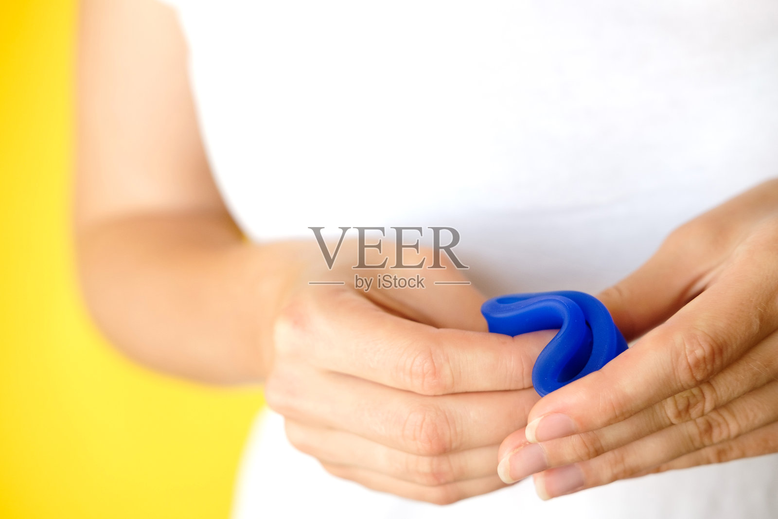 女人手里拿着折叠的蓝色月经杯。女性卫生用品代替卫生棉条。月经,关键日子,女性月经。32、零浪费,生态,生态。近距离照片摄影图片