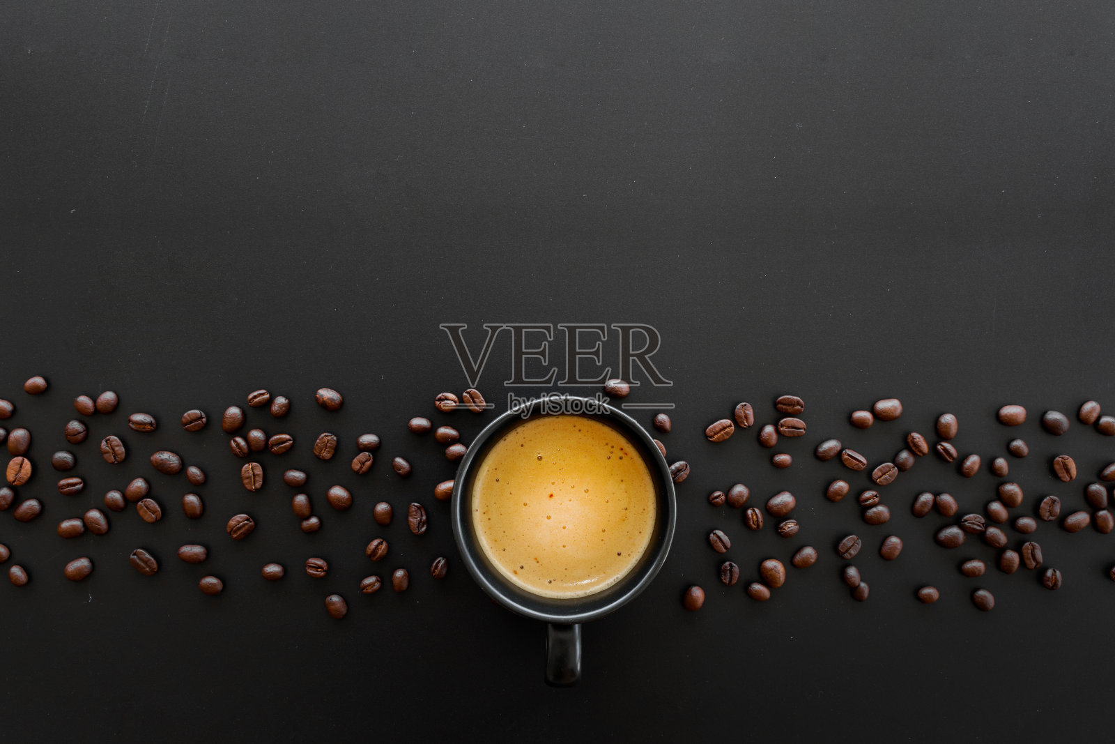 黑色的桌子上放着热意式浓缩咖啡和咖啡豆,背景是软焦和过光。俯视图照片摄影图片