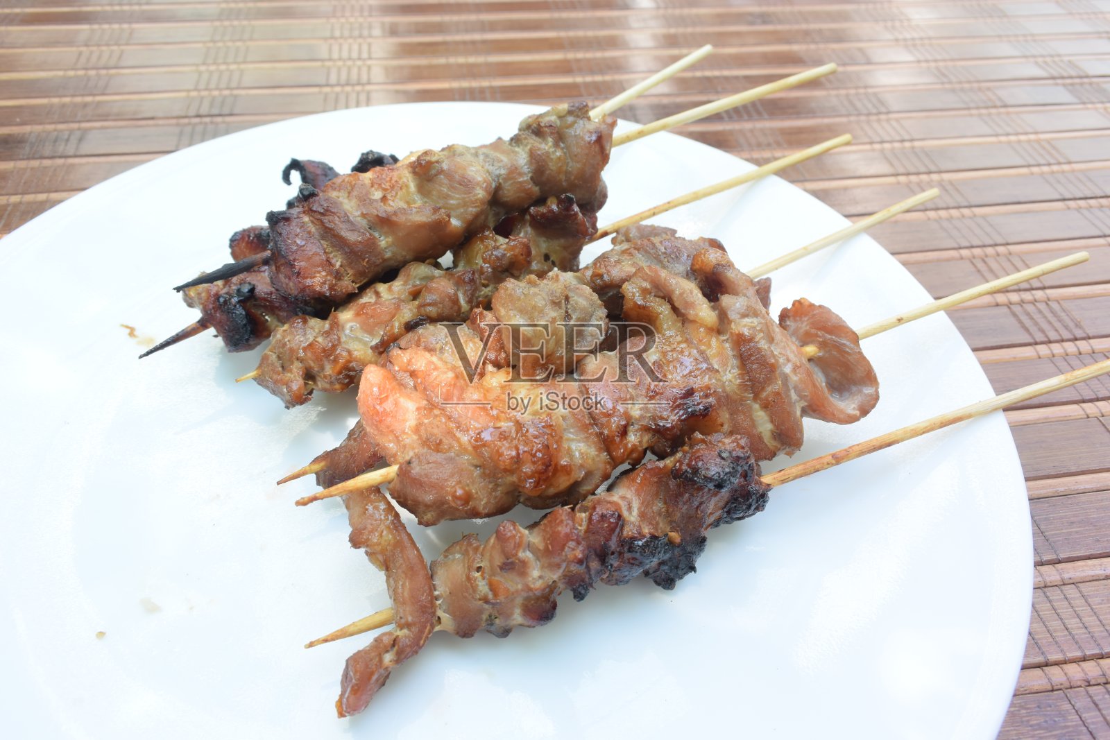 用竹签把猪肉串在烤架上照片摄影图片