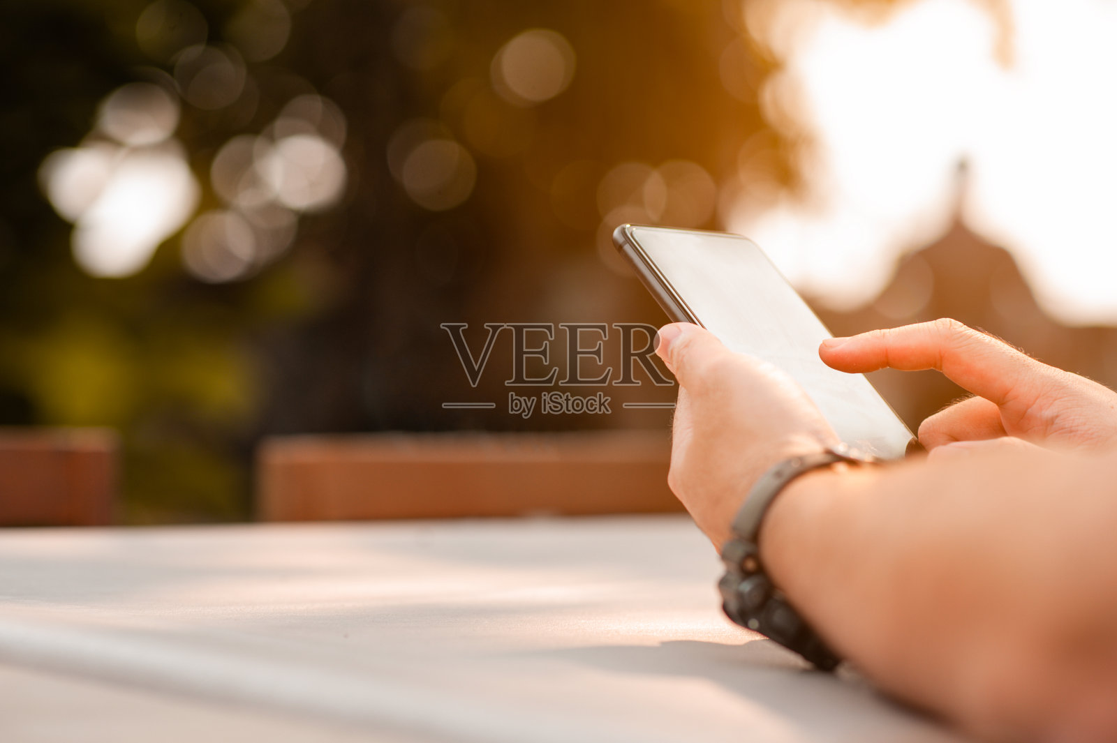 一个男人使用移动智能手机的特写。夏天,男人在户外使用智能手机。照片摄影图片