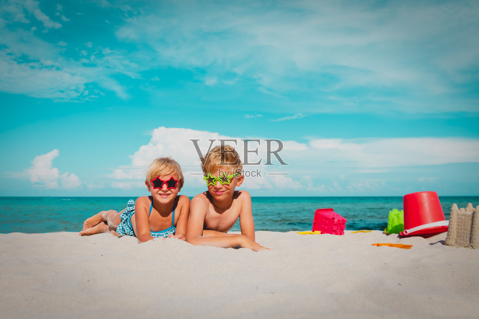 可爱的孩子们——男孩和女孩——在海滩上玩玩具和沙子照片摄影图片