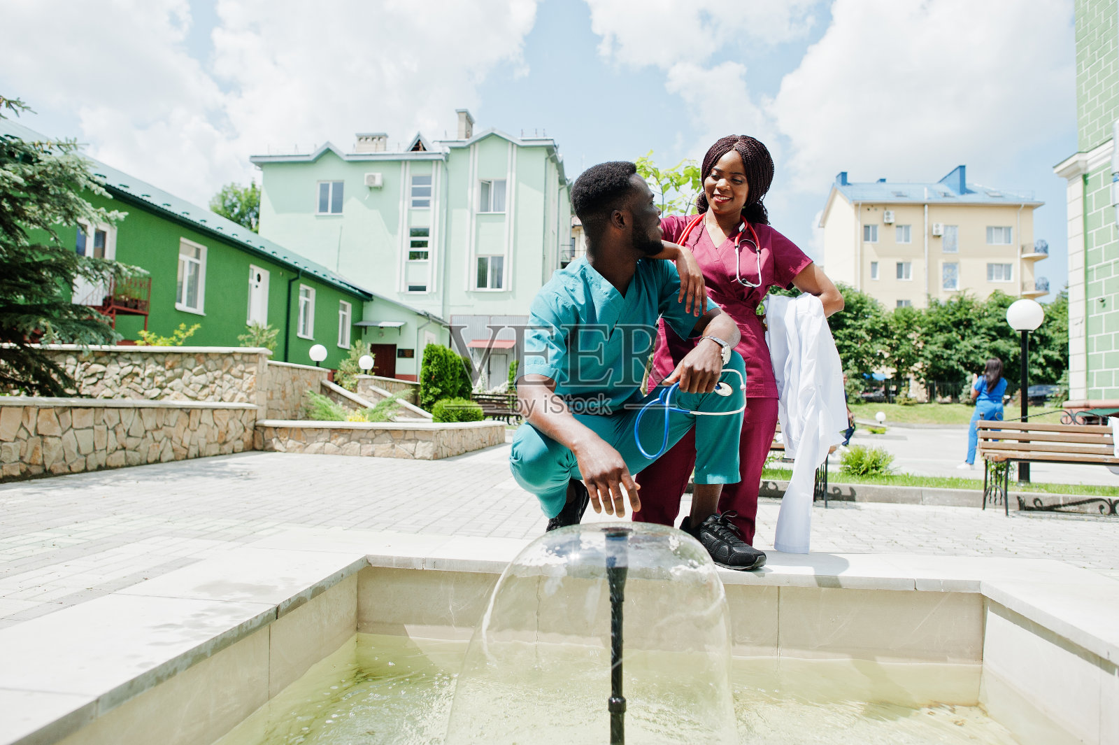 两个年轻美丽的非洲裔美国夫妇医生在大衣与听诊器对医院的后院。照片摄影图片