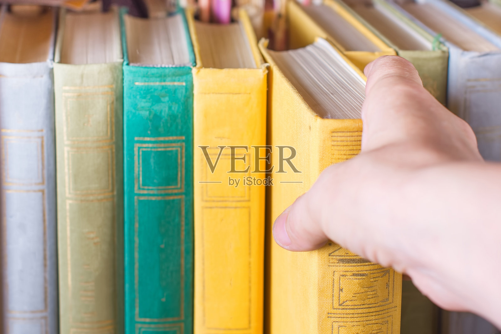 一只手从书架上挑选一本书照片摄影图片