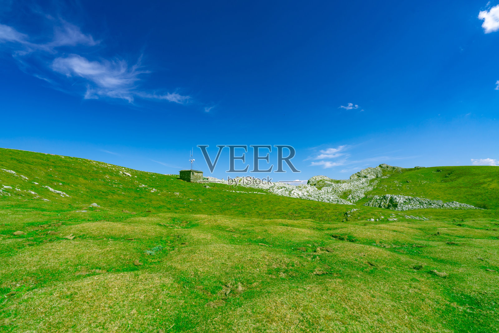 春天有美丽的蓝天白云,绿草如茵,石山如画。乡村或乡村景色。阳光明媚的大自然背景。新鲜空气的环境。山上的石头。照片摄影图片