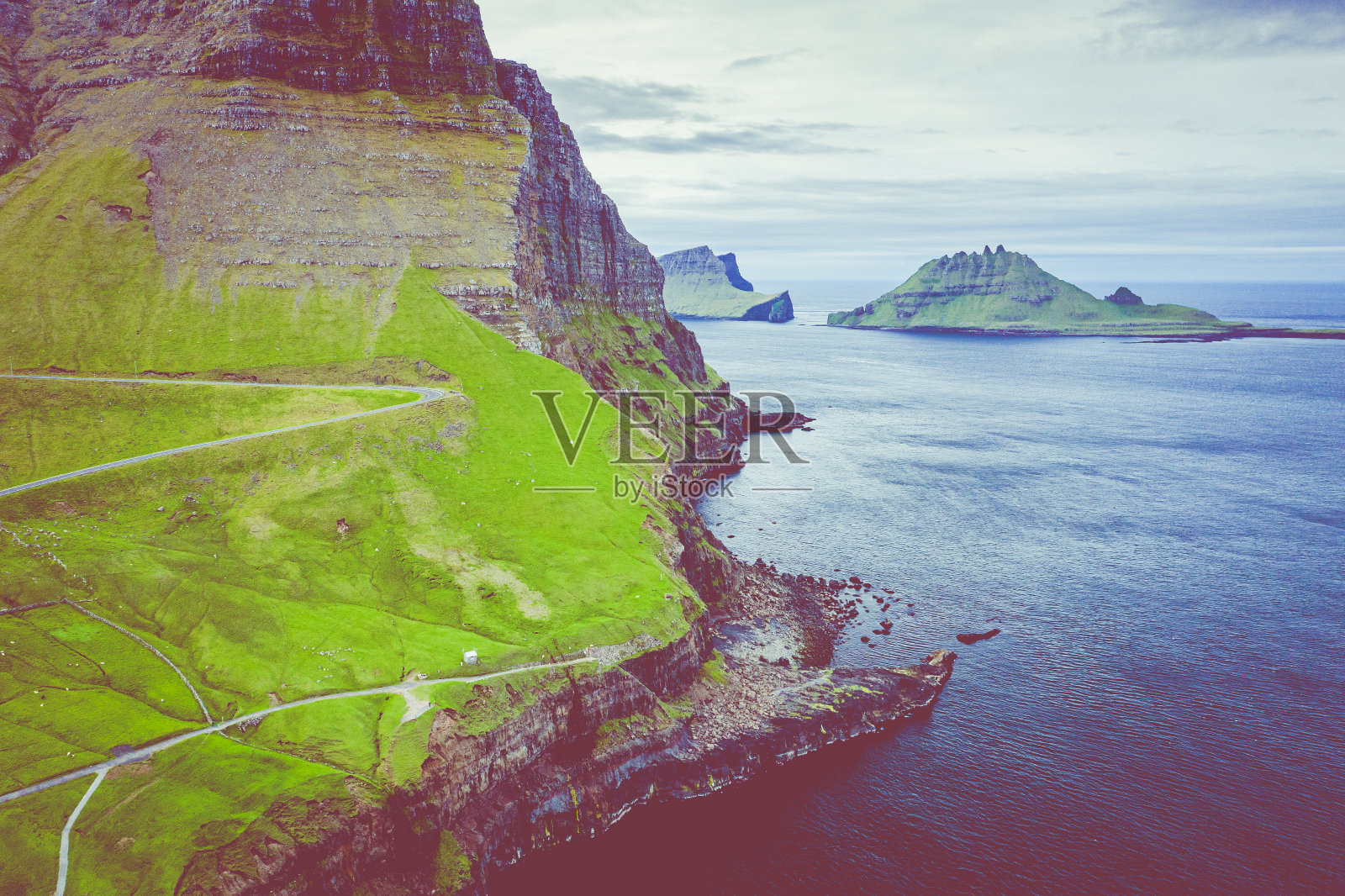 在北大西洋法罗群岛Gasadalur村的Mulafossur瀑布鸟瞰图。无人机从上面拍摄的照片。北欧自然景观。照片摄影图片