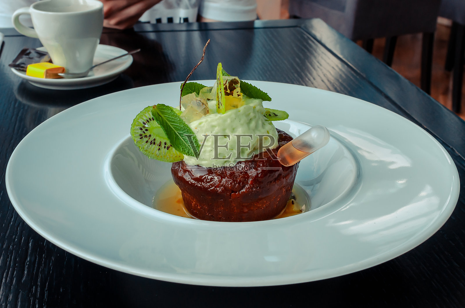 餐厅里的巧克力蛋糕配白兰地。纸杯蛋糕用猕猴桃、薄荷叶和水果果冻装饰。照片摄影图片