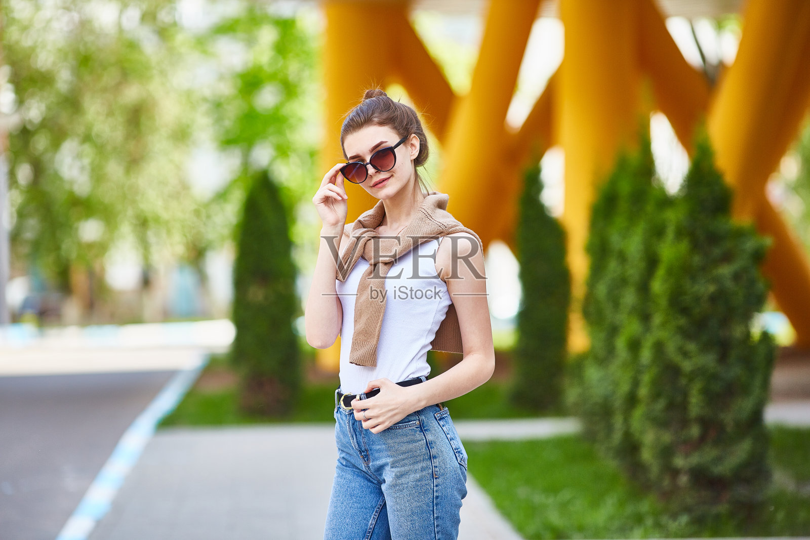 一个小女孩在一个夏日里走着,看着镜头。城市的风格。照片摄影图片