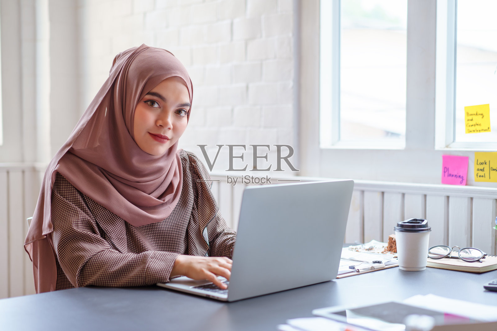 快乐的阿拉伯裔职业女商人戴着棕色头巾在家工作照片摄影图片