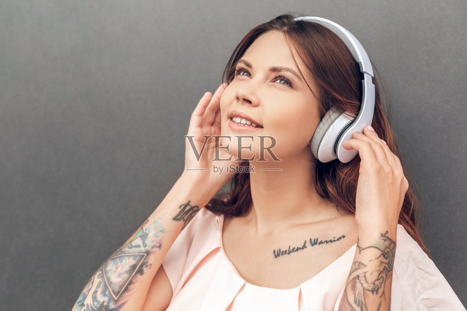 自由泳。戴着耳机的女孩孤立地站在灰色的城市街道上听着最喜欢的歌曲微笑着梦幻般的特写照片摄影图片