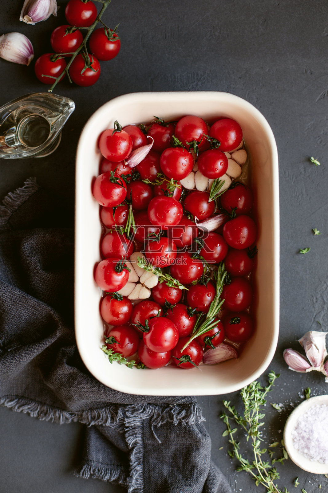 准备的过程烤樱桃番茄与香草和大蒜。乡村背景。照片摄影图片