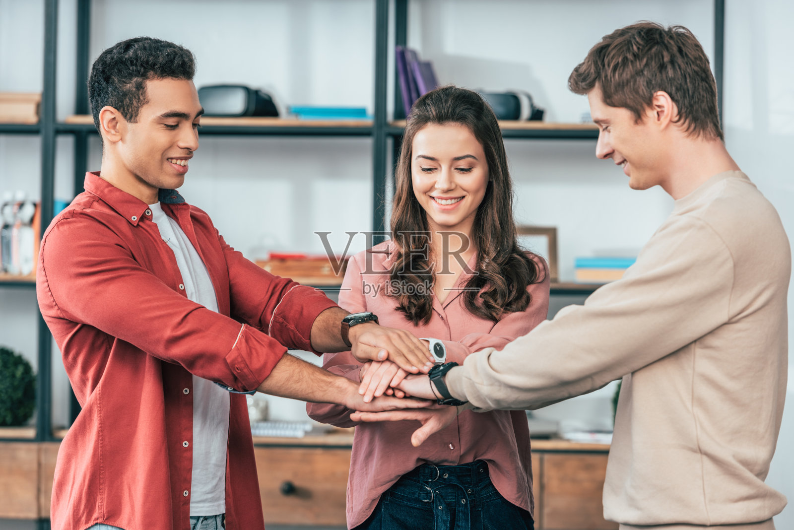 三位来自不同文化背景的朋友在家里微笑着双手合十照片摄影图片