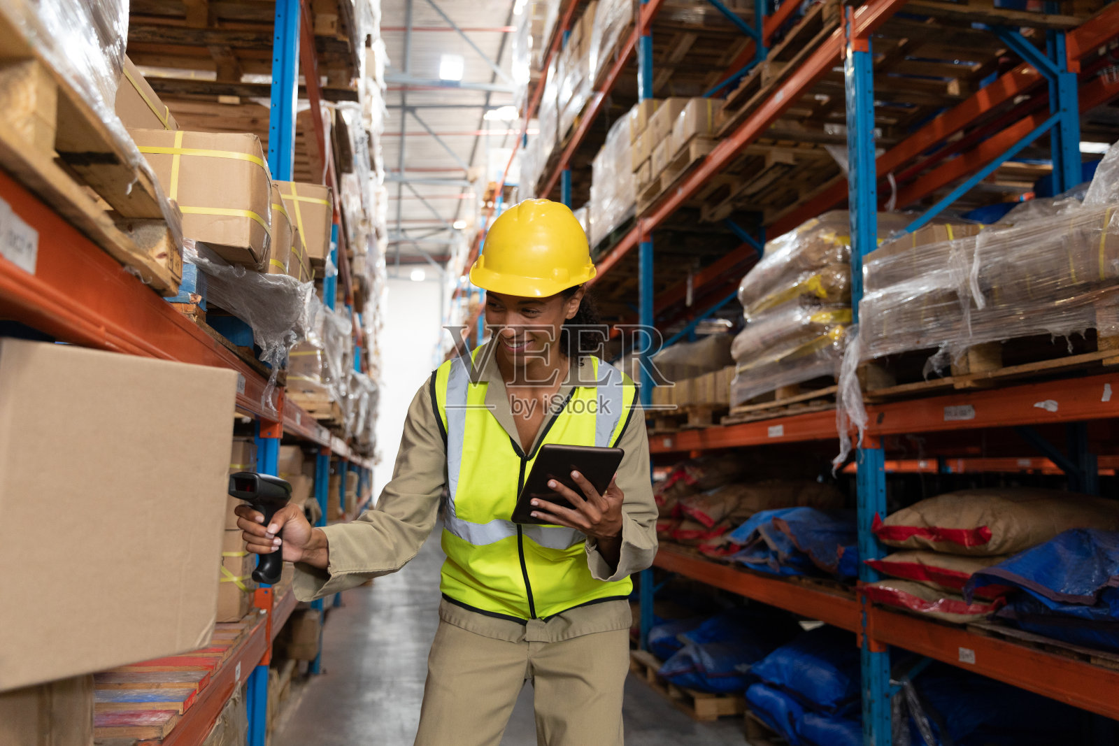 女工在仓库使用平板电脑时,用条码扫描仪扫描包裹照片摄影图片