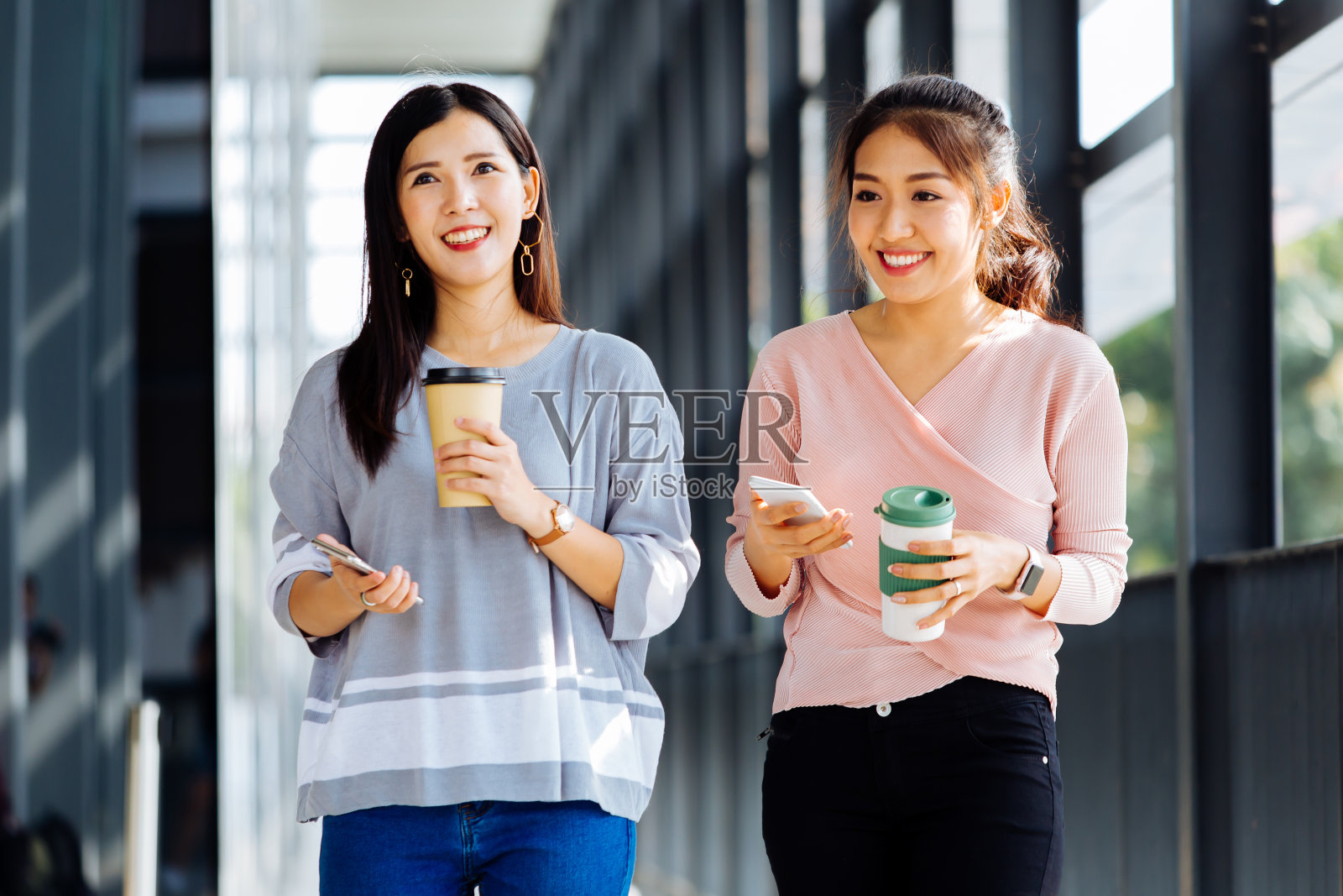 年轻的亚洲商务女性穿着休闲装在办公大楼里交谈照片摄影图片