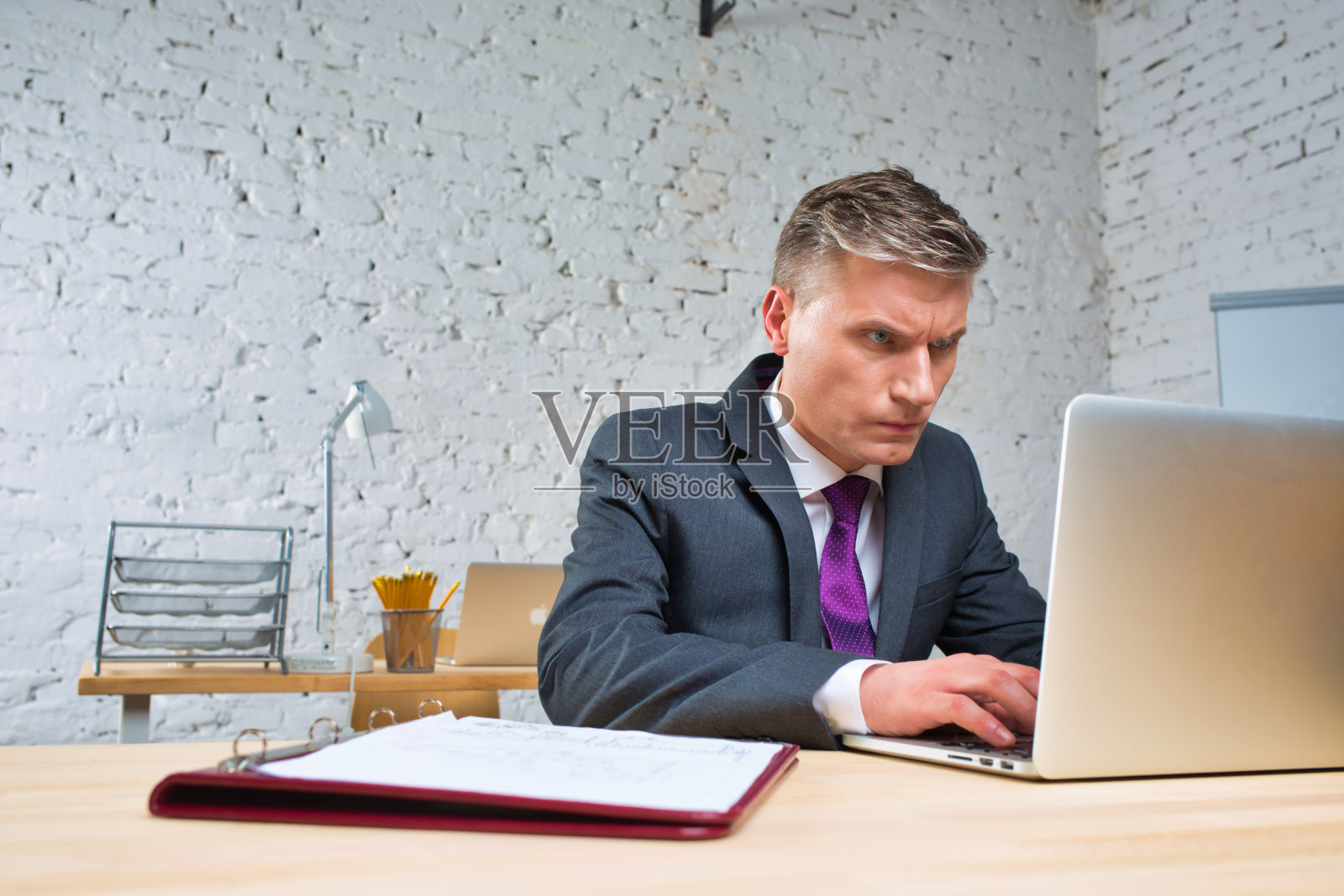 劳累过度的成熟商人看着办公桌上的笔记本电脑照片摄影图片