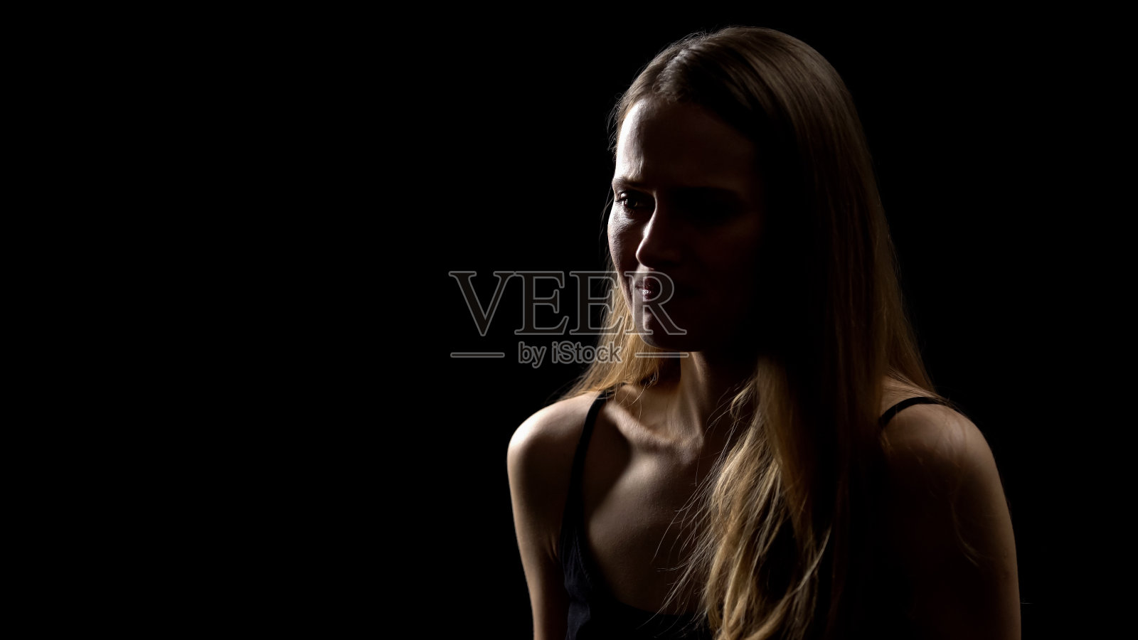 悲伤的女人哭泣,在黑色背景下感到沮丧,对坏消息和问题感到不安。照片摄影图片