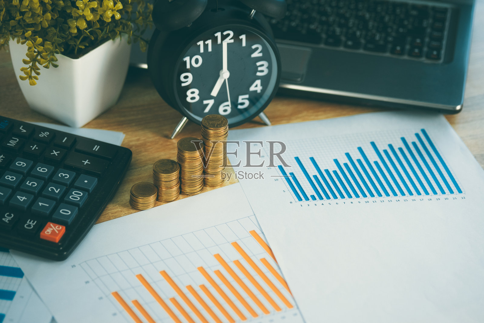 硬币堆叠和财务图表纸与笔记本计算器和闹钟的工作台上的业务概念。照片摄影图片