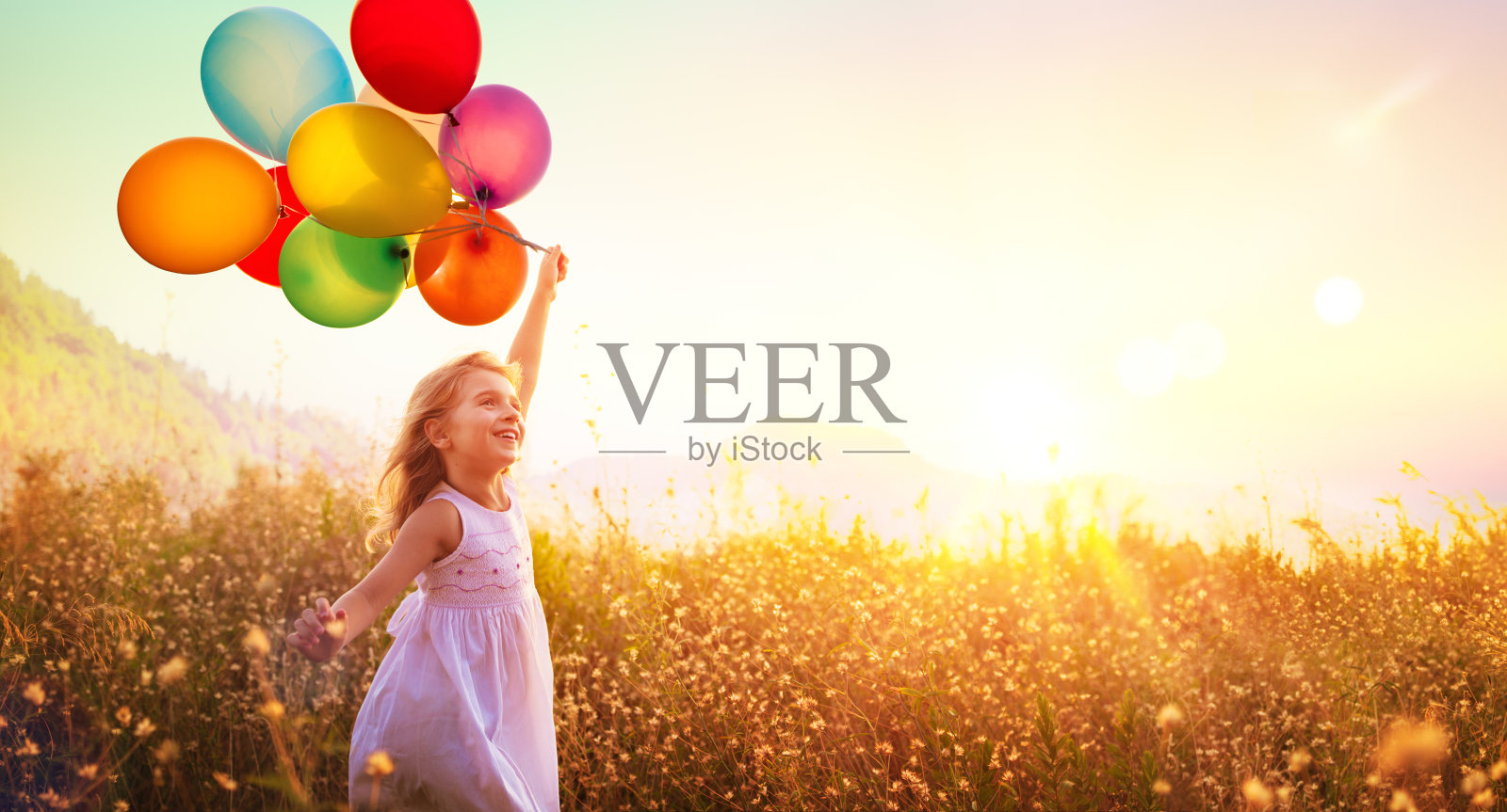 快乐的孩子与气球在田野在日落照片摄影图片