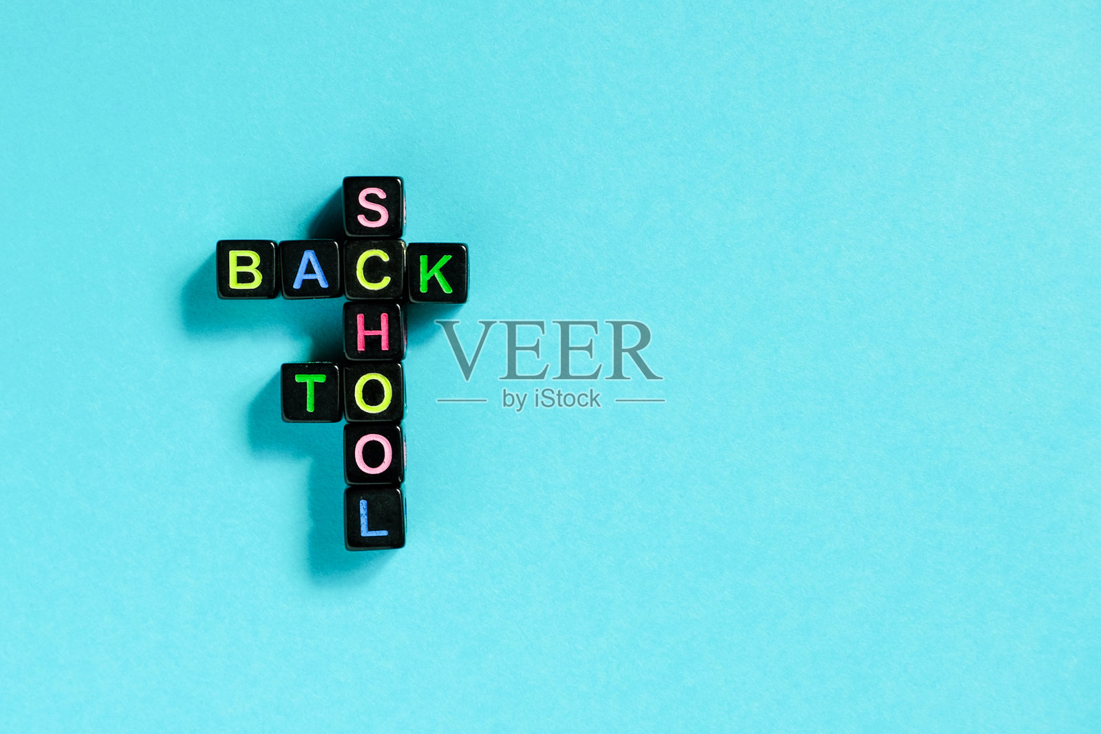 回到学校,文字由彩色的字母在黑色的方块上排列成纵横字谜的形式,蓝色的背景。概念教育和学年开始复制空间俯视图平面布局照片摄影图片