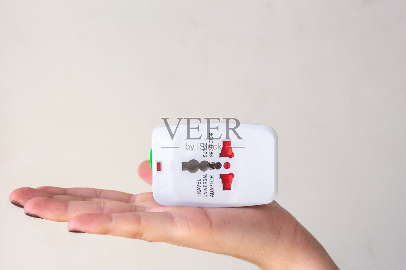 女性手握通用插座插头适配器,隔离在白色背景。用于连接世界各地的电源插座。解决方案、旅行和技术的概念。照片摄影图片